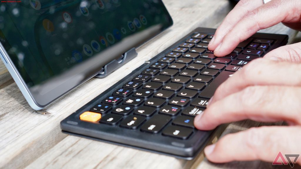 لوحة ProtoArc XK04 القابلة للطي موضوعة بجانب جهاز OnePlus Pad Lite أثناء العمل في مقهى